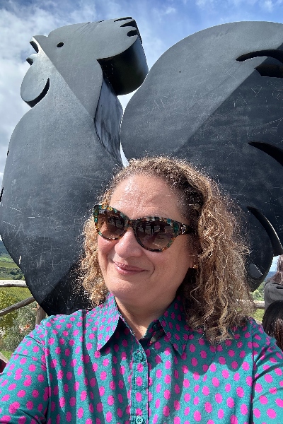 A woman standing in front of the Black Rooster sculpture in Panzano in Chianti, Italy.