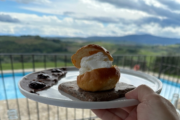 A plated maritozzo cream bun on the terrace at Passo Dopo Passo Osteria in Tuscany, Italy.